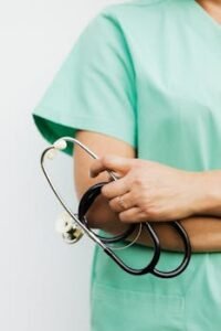 Close-up of a healthcare professional in scrubs holding a stethoscope.